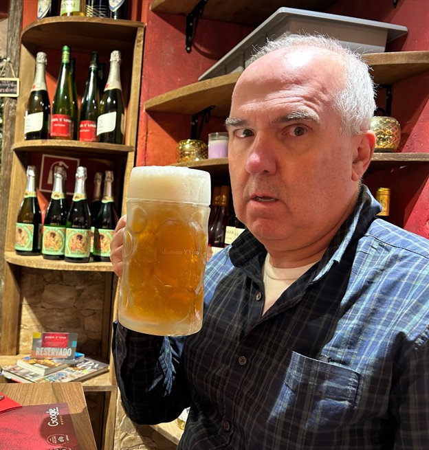 A selfie photograph of Dan Malleck standing in a pub and holding a pint of beer.
